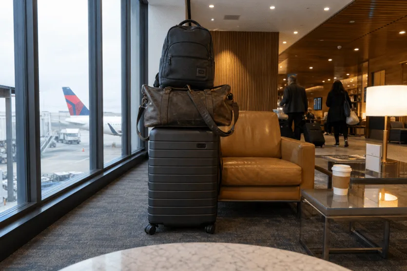 Front-camera view from an iPad in an airport lounge — a pile of luggage watched by the window.